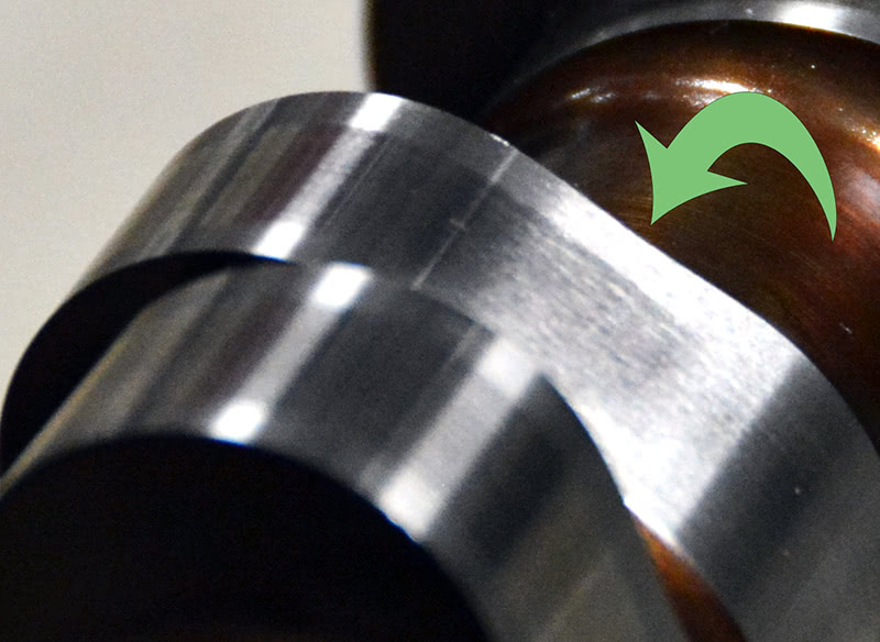 This particular cam has a pretty good inverse ramp on both the opening and closing side of the lobe. If you look right at the arrow, you can see that there is a dip in the lobe face. You can also see the mark left by the wheel as it came off lash and engaged the lobe. This cam has a relatively small base circle with a fair amount of lift, so these ramps are used to help control the rate of acceleration. if-you-look-closely-you-can-see-the-inverse-ramp-used-to-control-roller-lifter-acceleration